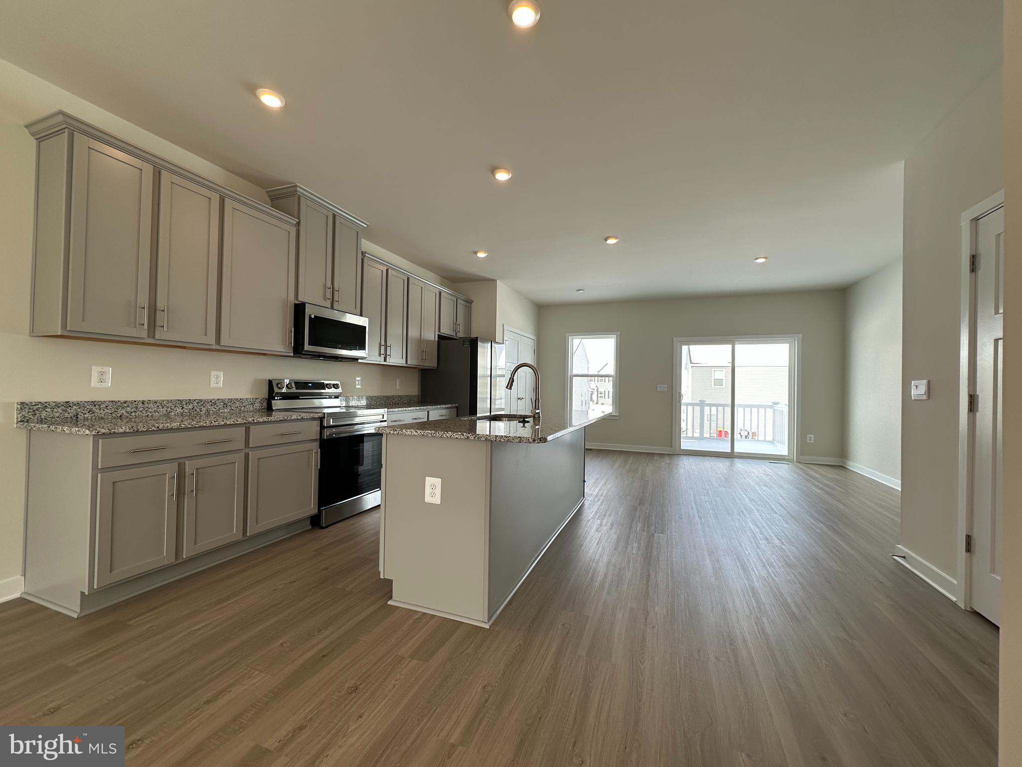 69 Trotting Road Inwood, WV 25428 - Photo 10 of 43 a kitchen with stainless steel appliances a microwave a stove a sink dishwasher a refrigerator and white cabinets with wooden floor