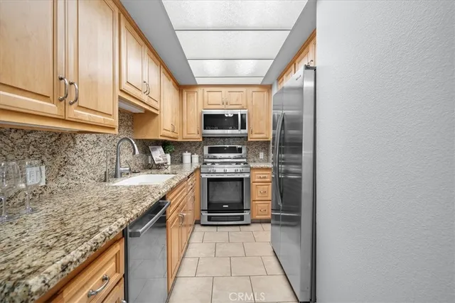 a kitchen with granite countertop a stove sink and microwave