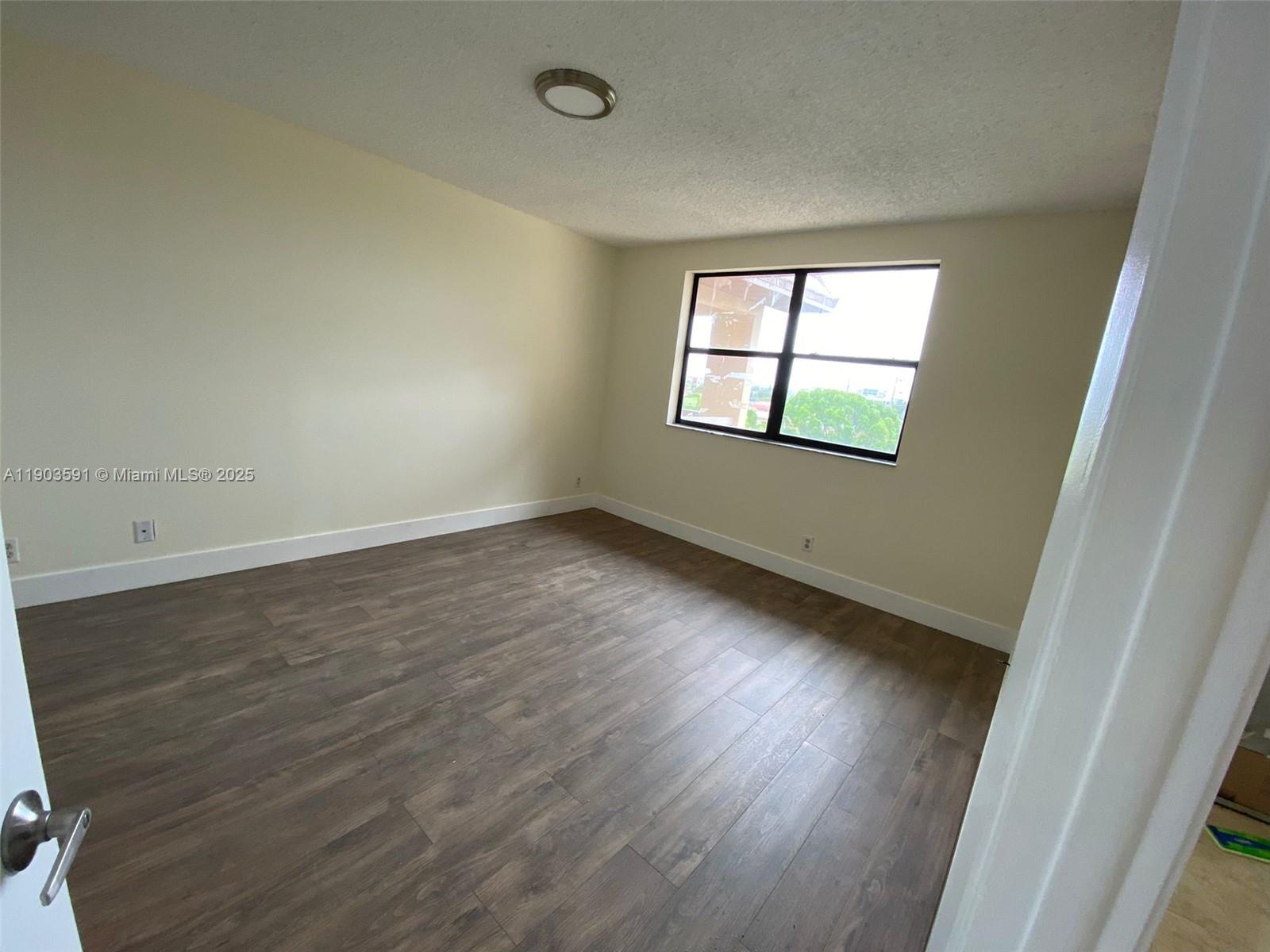 8120 Geneva Court, Unit 554 Doral, FL 33166 - Photo 16 of 32 an empty room with wooden floor and windows