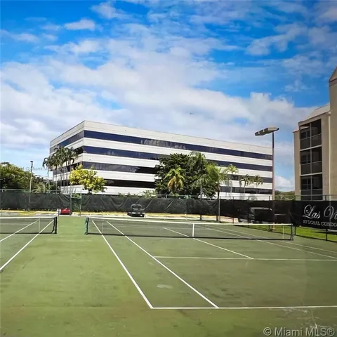a view of a tennis ground with large trees