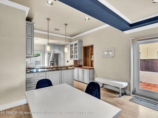a kitchen with stainless steel appliances kitchen island granite countertop a refrigerator a sink a stove and white cabinets with wooden floor