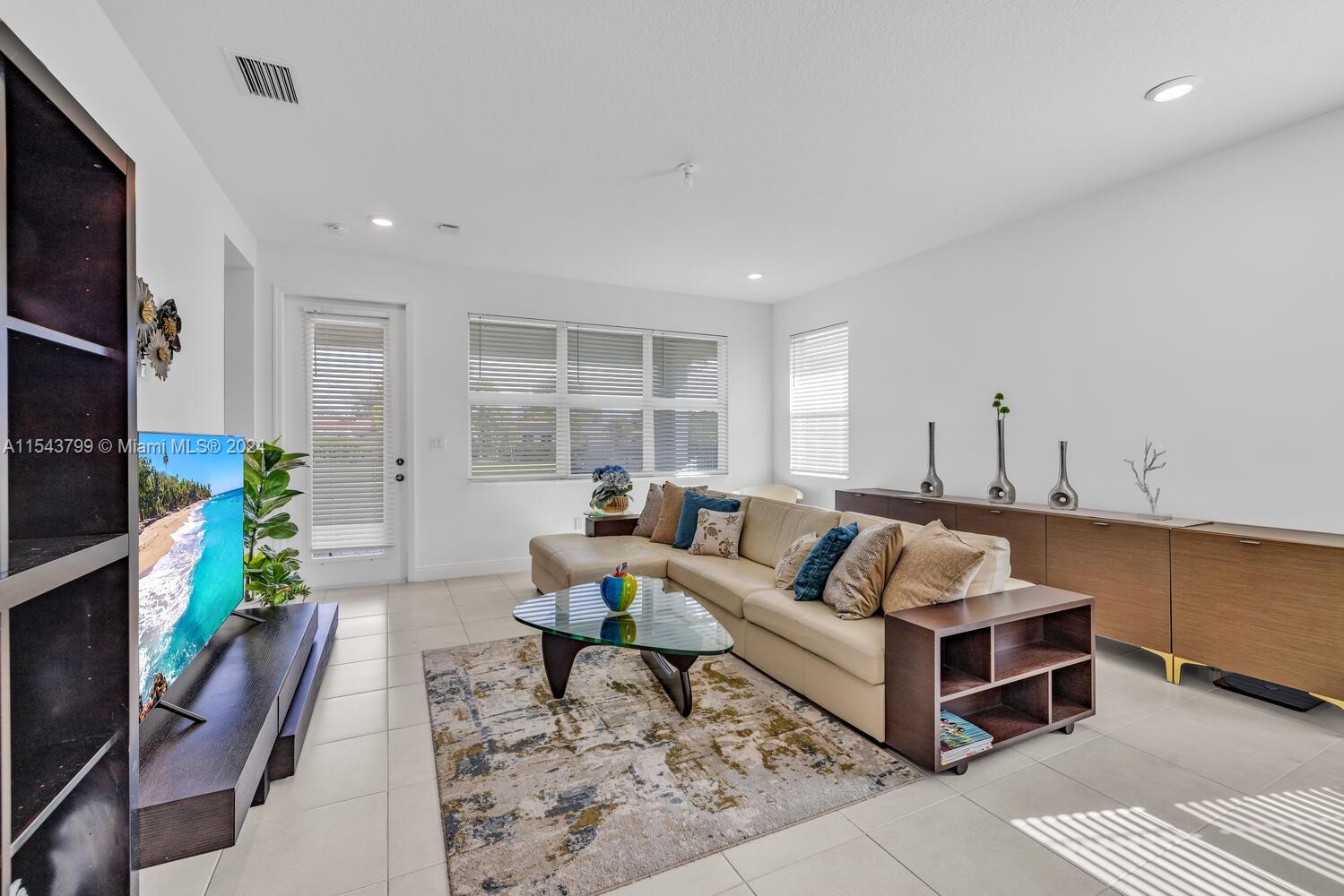 4242 Rosa Drive, Unit 4242 Deerfield Beach, FL 33064 - Photo 3 of 32 a living room with furniture a flat screen tv and a table
