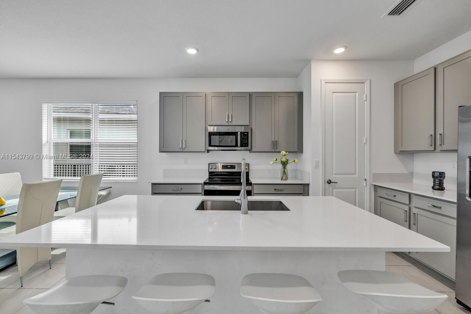 4242 Rosa Drive, Unit 4242 Deerfield Beach, FL 33064 - Photo 9 of 32 a kitchen with stainless steel appliances a stove a sink a microwave and white cabinets