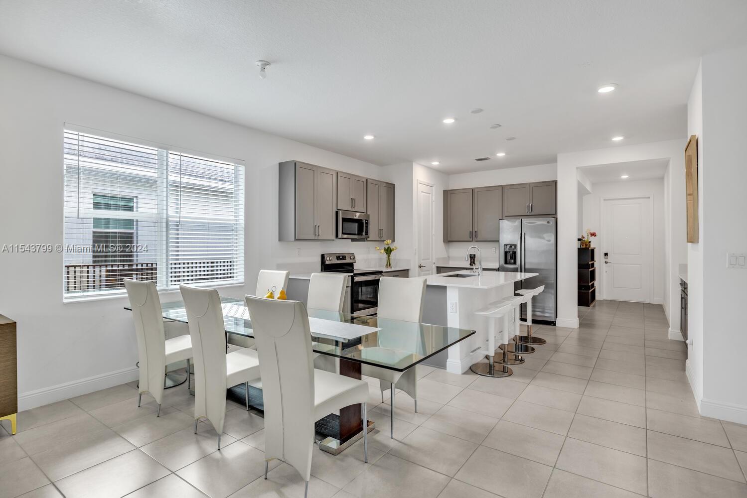 4242 Rosa Drive, Unit 4242 Deerfield Beach, FL 33064 - Photo 10 of 32 a kitchen with a dining table chairs and refrigerator