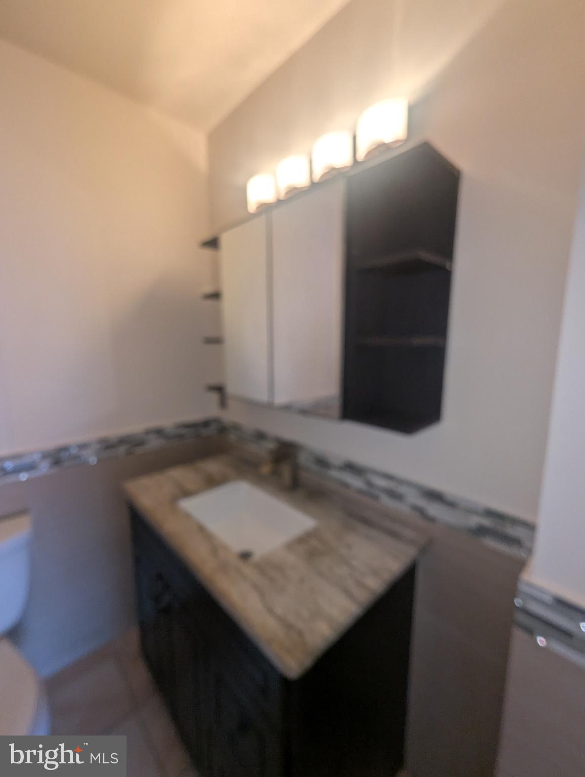 1624 West Diamond Street Philadelphia, PA 19121 - Photo 31 of 38 a bathroom with a granite countertop sink and a mirror