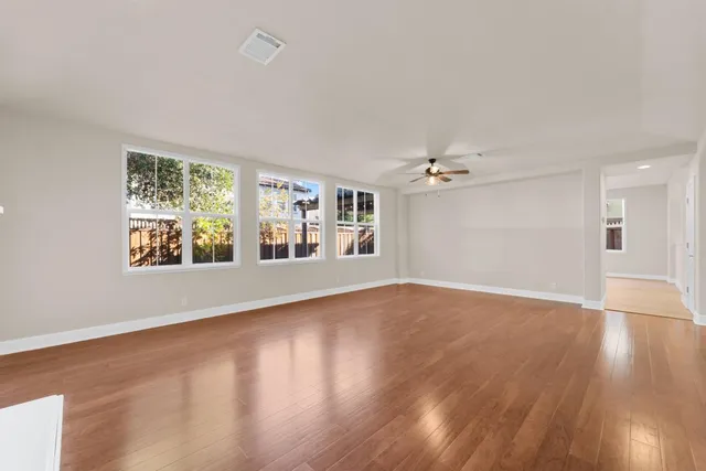 a view of an empty room with window and wooden floor