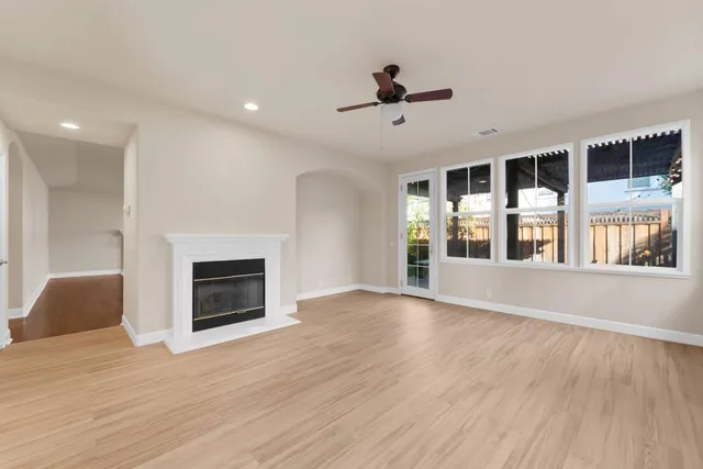 a view of an empty room with wooden floor fireplace and a window