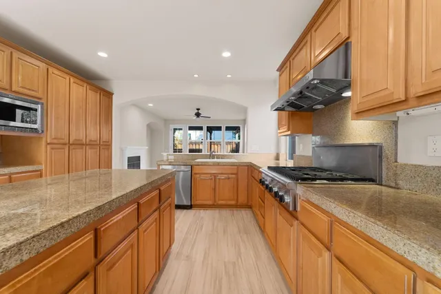 a kitchen with stainless steel appliances granite countertop a stove a sink and a microwave
