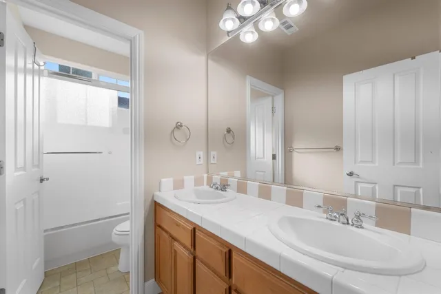 a bathroom with a granite countertop sink a toilet and a mirror