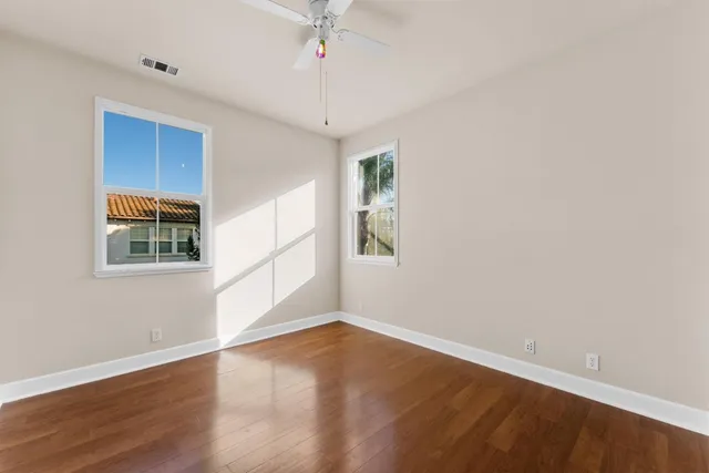 a view of empty room with wooden floor and fan
