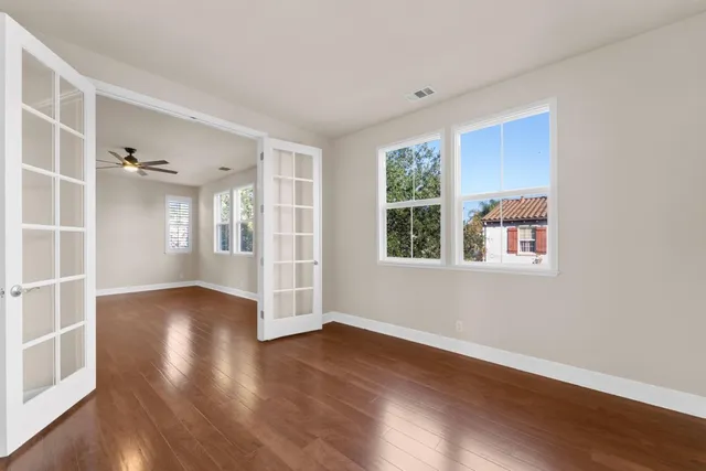 a view of an empty room with wooden floor and a window