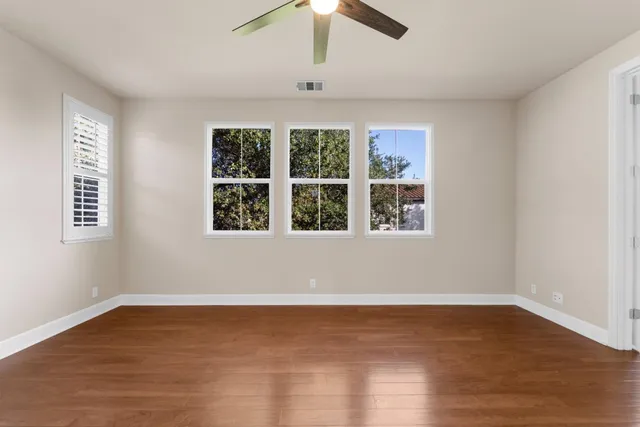 a view of an empty room with wooden floor and windows