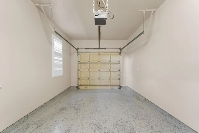 an empty room with chandelier fan and windows