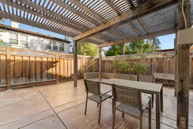 a patio with table and chairs and potted plants with wooden floor and fence