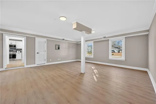 a view of an empty room with window and wooden floor