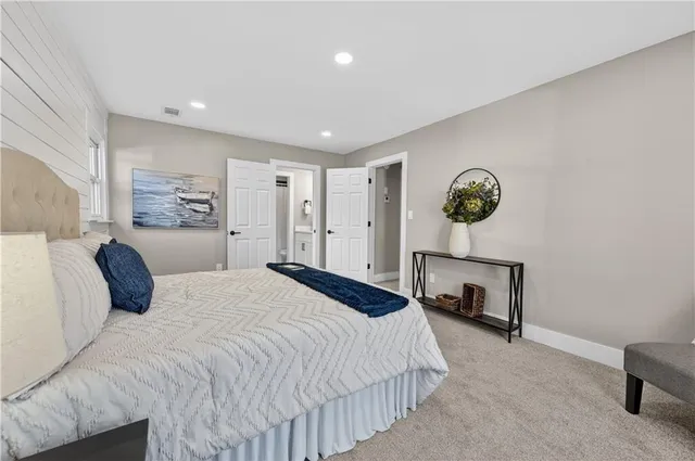 a spacious bedroom with a bed and a lamp