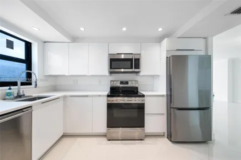 a kitchen with a sink a refrigerator and a stove top oven with wooden floor