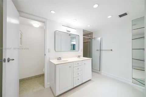 a spacious bathroom with a double vanity sink a mirror and a shower