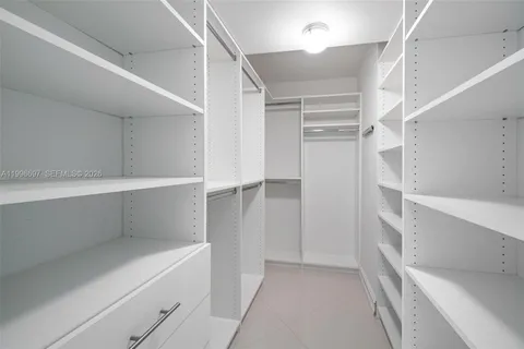 a view of a hallway with wooden floor and kitchen space