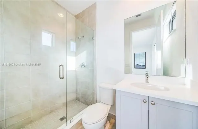 a bathroom with a shower sink vanity mirror and toilet