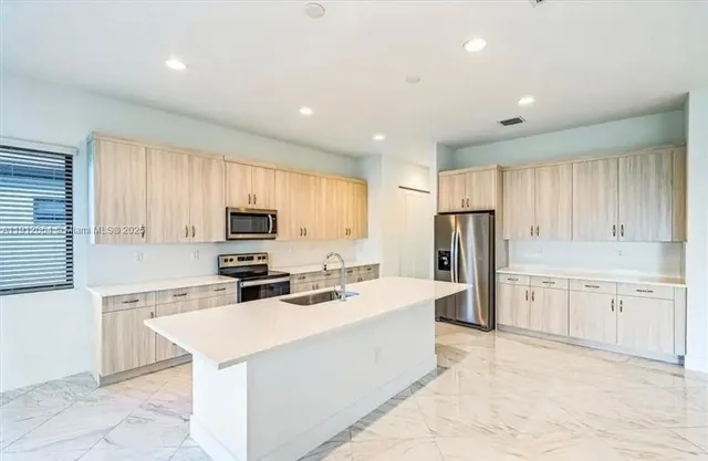 a kitchen with stainless steel appliances sink stove refrigerator and cabinets