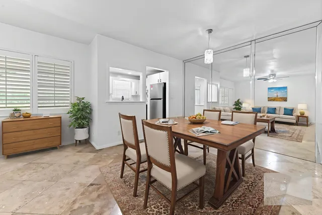 a dining hall with stainless steel appliances kitchen island granite countertop a table chairs and a refrigerator