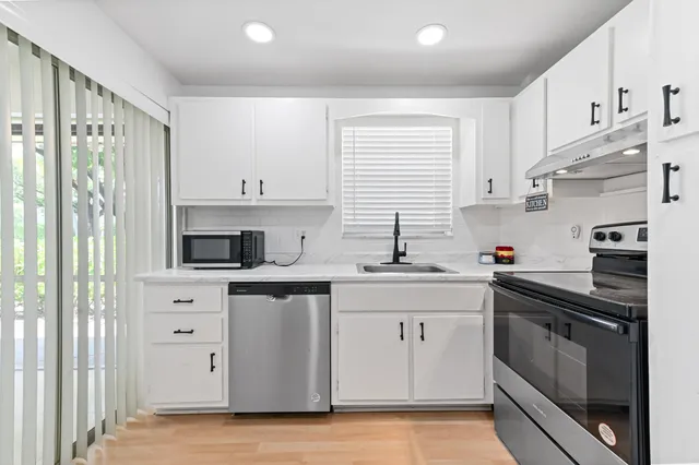 a kitchen with stainless steel appliances a sink stove and cabinets