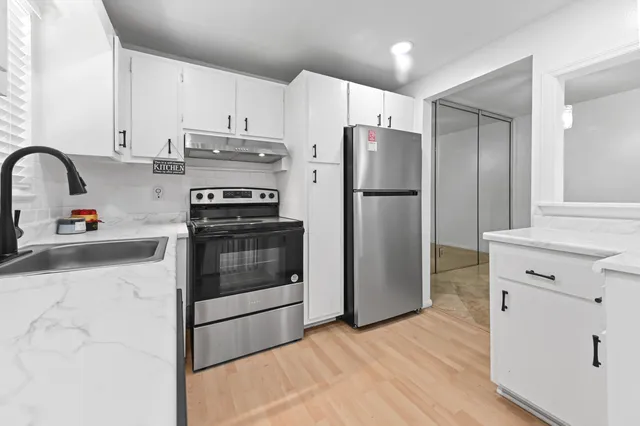 a kitchen with a refrigerator stove and white cabinets