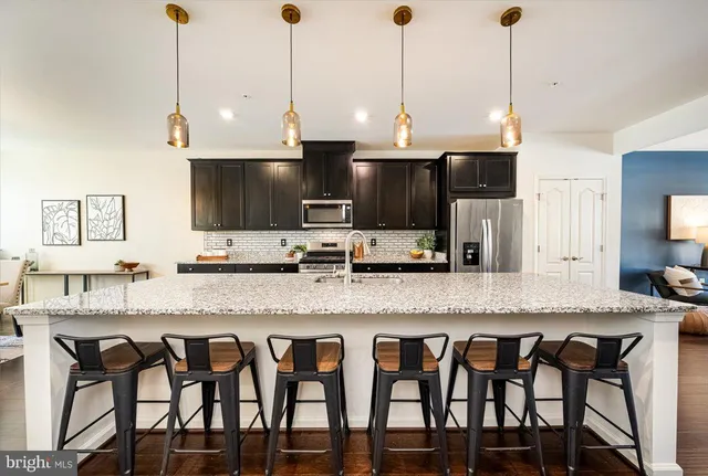a kitchen with granite countertop a stove a sink and a chairs