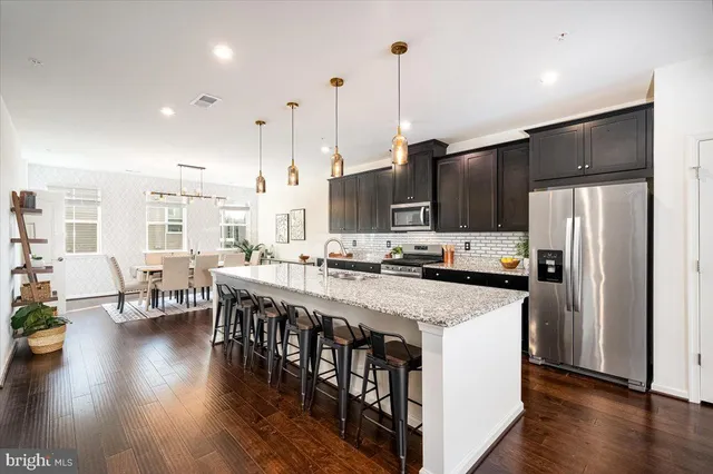 a kitchen with stainless steel appliances granite countertop a table chairs stove a refrigerator and cabinets