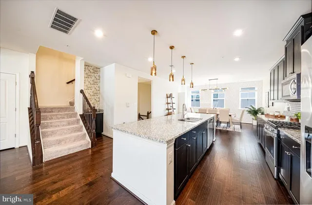 a kitchen with stainless steel appliances sink stove and wooden floor