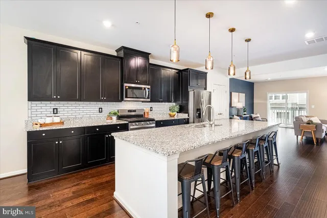 a kitchen with stainless steel appliances kitchen island granite countertop a stove a sink a oven a dining table and chairs