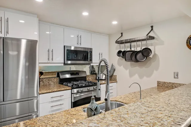 a kitchen with stainless steel appliances granite countertop a refrigerator and a stove top oven