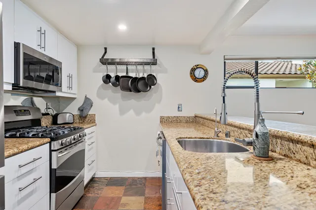 a kitchen with stainless steel appliances granite countertop a sink and a microwave