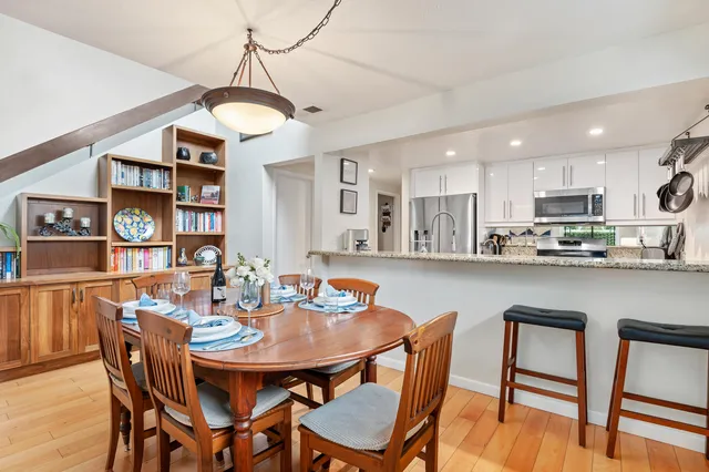 a kitchen with stainless steel appliances granite countertop a dining table chairs and white cabinets