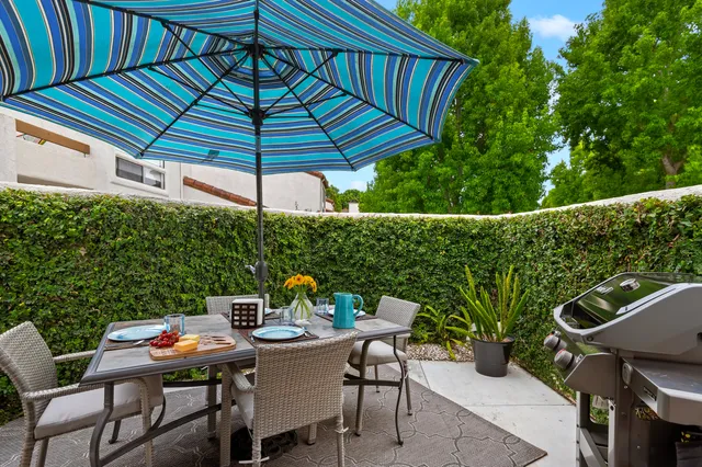 a patio with wooden floor a yard a table and chairs