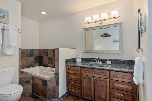 a bathroom with a granite countertop sink a toilet and mirror