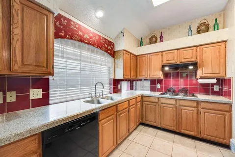 a kitchen with a sink dishwasher window and cabinets