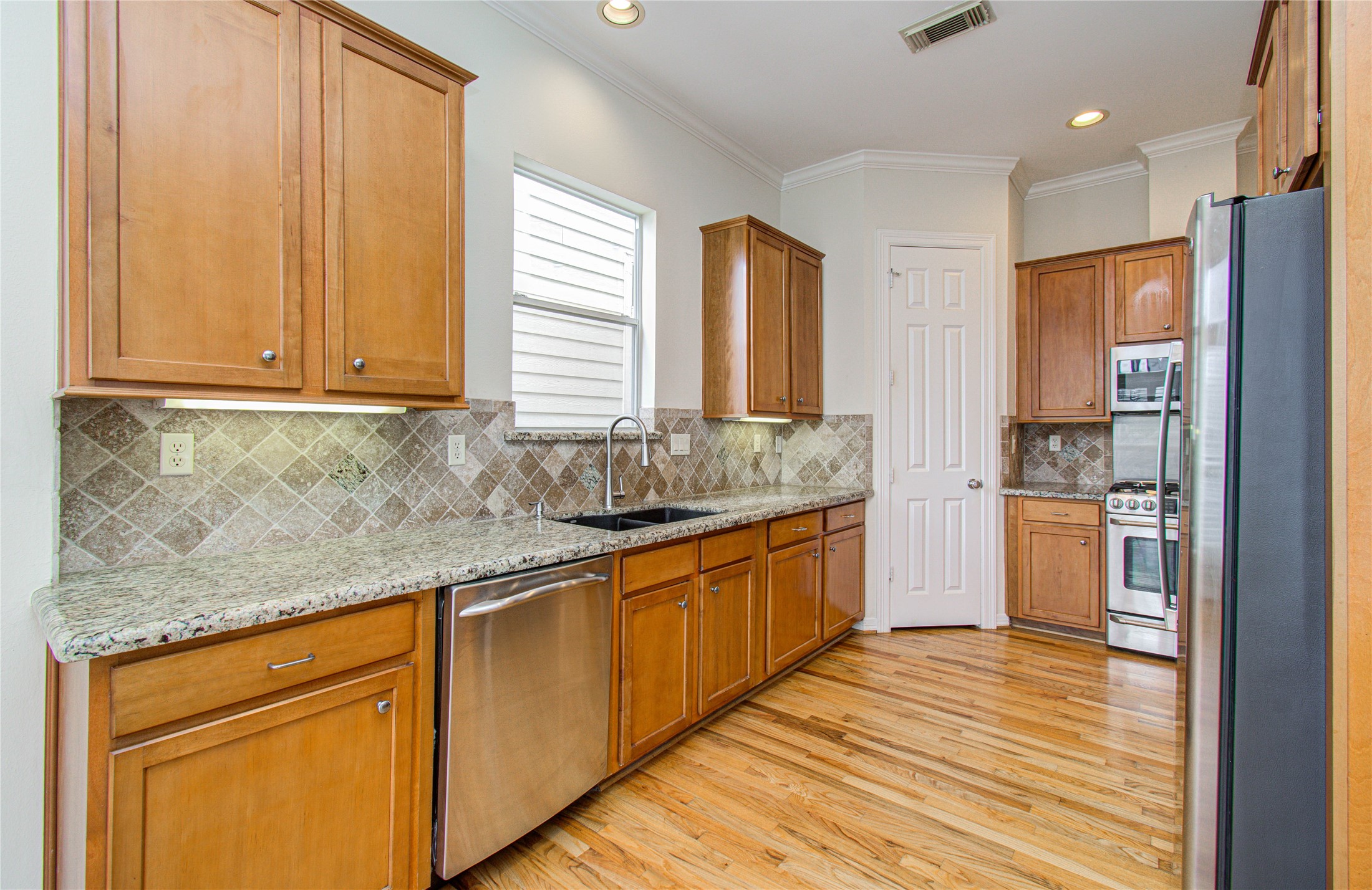 501 Leverkuhn Street Houston, TX 77007 - Photo 13 of 31 a kitchen with stainless steel appliances granite countertop wooden cabinets a sink and dishwasher with wooden floor