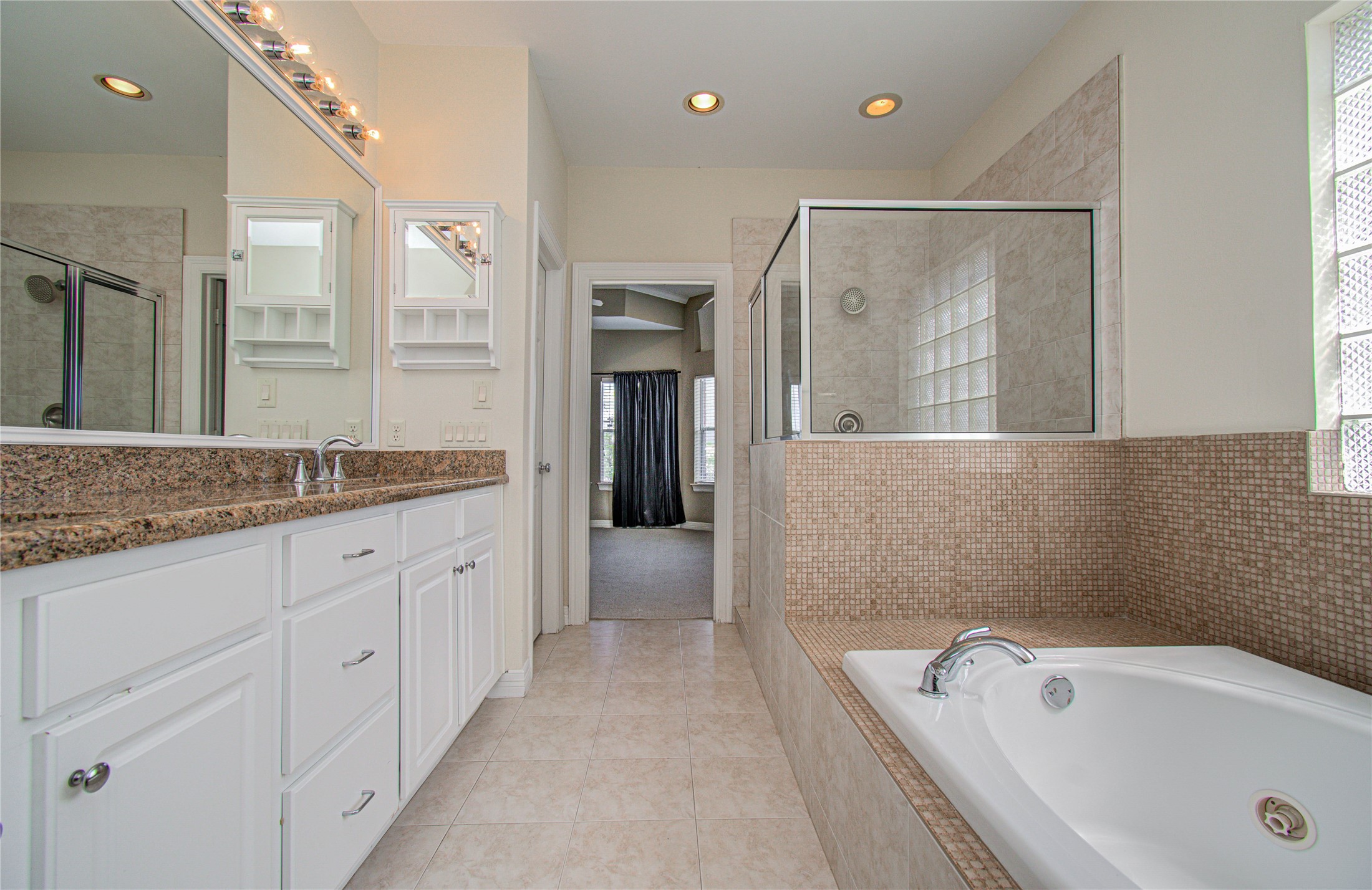 501 Leverkuhn Street Houston, TX 77007 - Photo 27 of 31 a spacious bathroom with a granite countertop tub a double vanity sink and a mirror