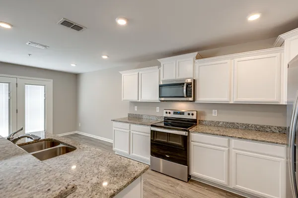 a kitchen with granite countertop a stove sink and cabinets