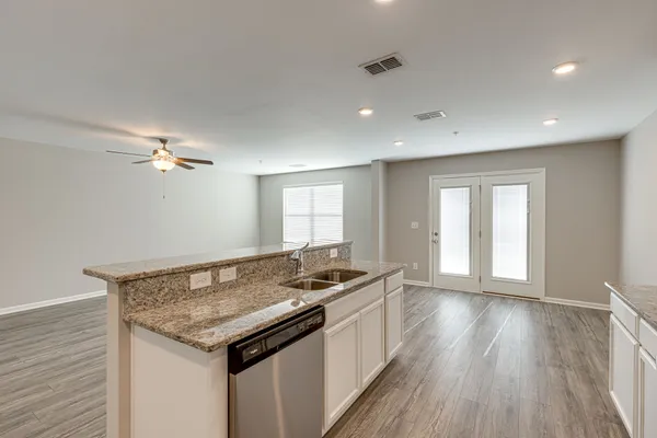 a kitchen that has a sink a microwave oven a stove and white cabinets with wooden floor