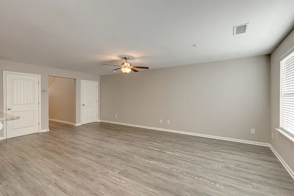 a view of an empty room with wooden floor and window