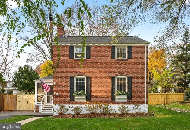 a front view of a house with a garden and trees