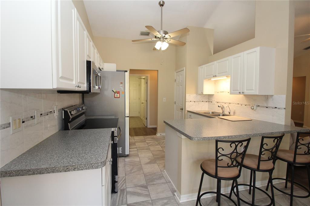 7432 Perennial Road North Port, FL 34291 - Photo 23 of 61 a kitchen with kitchen island granite countertop a sink a center island and cabinets