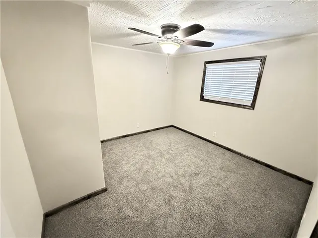 an empty room with a chandelier fan and wooden floor