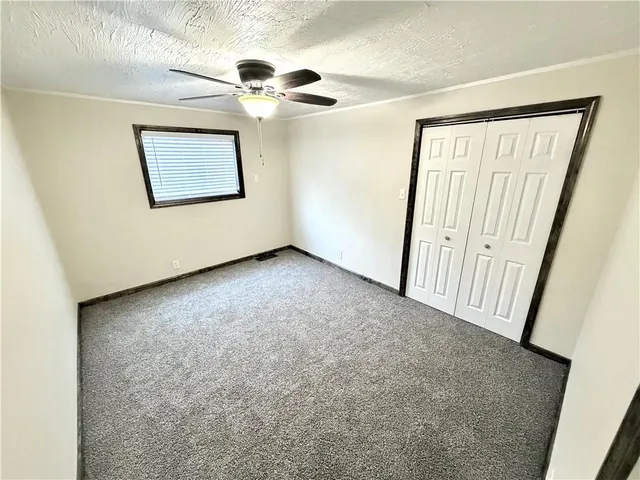 an empty room with a ceiling fan and a window