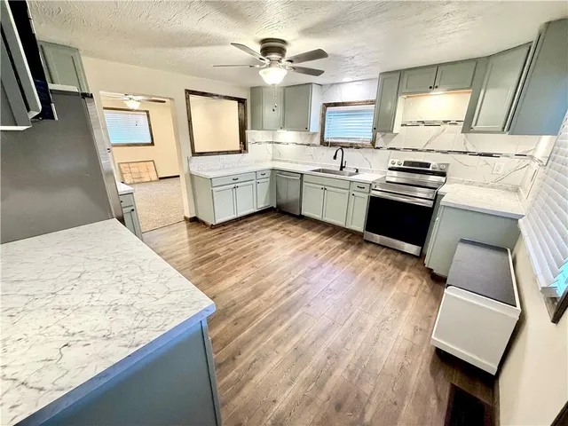 a kitchen with a sink cabinets stainless steel appliances and wooden floor