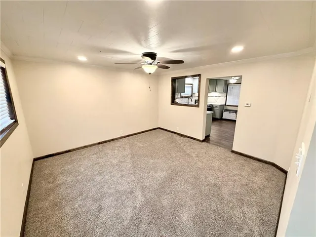 an empty room with ceiling fan and window