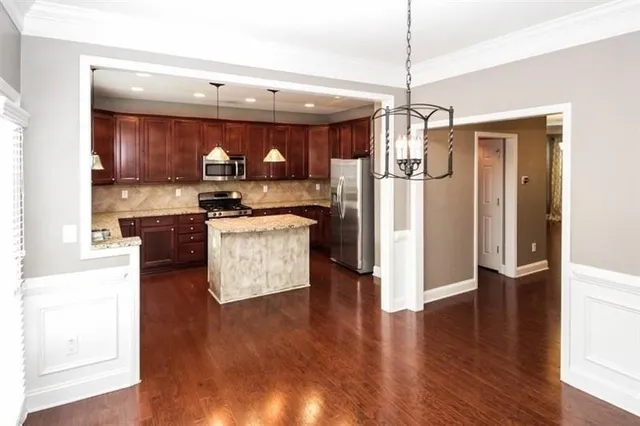 a kitchen with stainless steel appliances granite countertop a stove top oven a refrigerator a sink and dishwasher with wooden floor